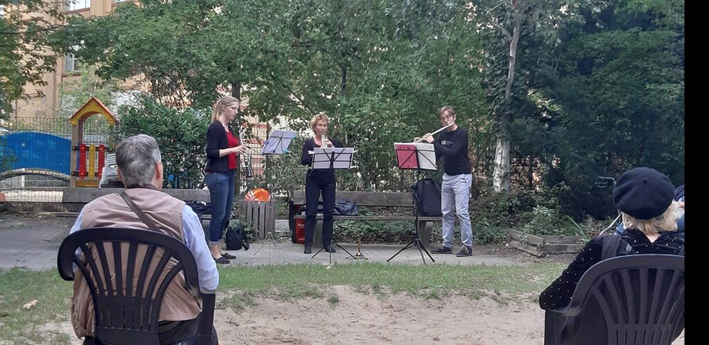 Musiker spielen im freien ein Konzert vor älteren Menschen.