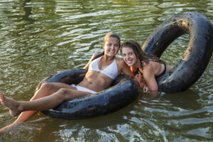 Zwei Mädchen schwimmen mit Schwimmringen im See.