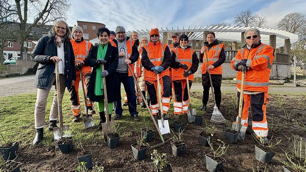 Die Bezirksbürgermeisterin, Katrin Lesser und Beschäftigte des Grünflächenamtes stehen mit Spaten an einem Rosenbeet auf dem Zeltinger Platz.