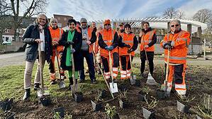 Die Bezirksbürgermeisterin, Katrin Lesser und Beschäftigte des Grünflächenamtes stehen mit Spaten an einem Rosenbeet auf dem Zeltinger Platz.