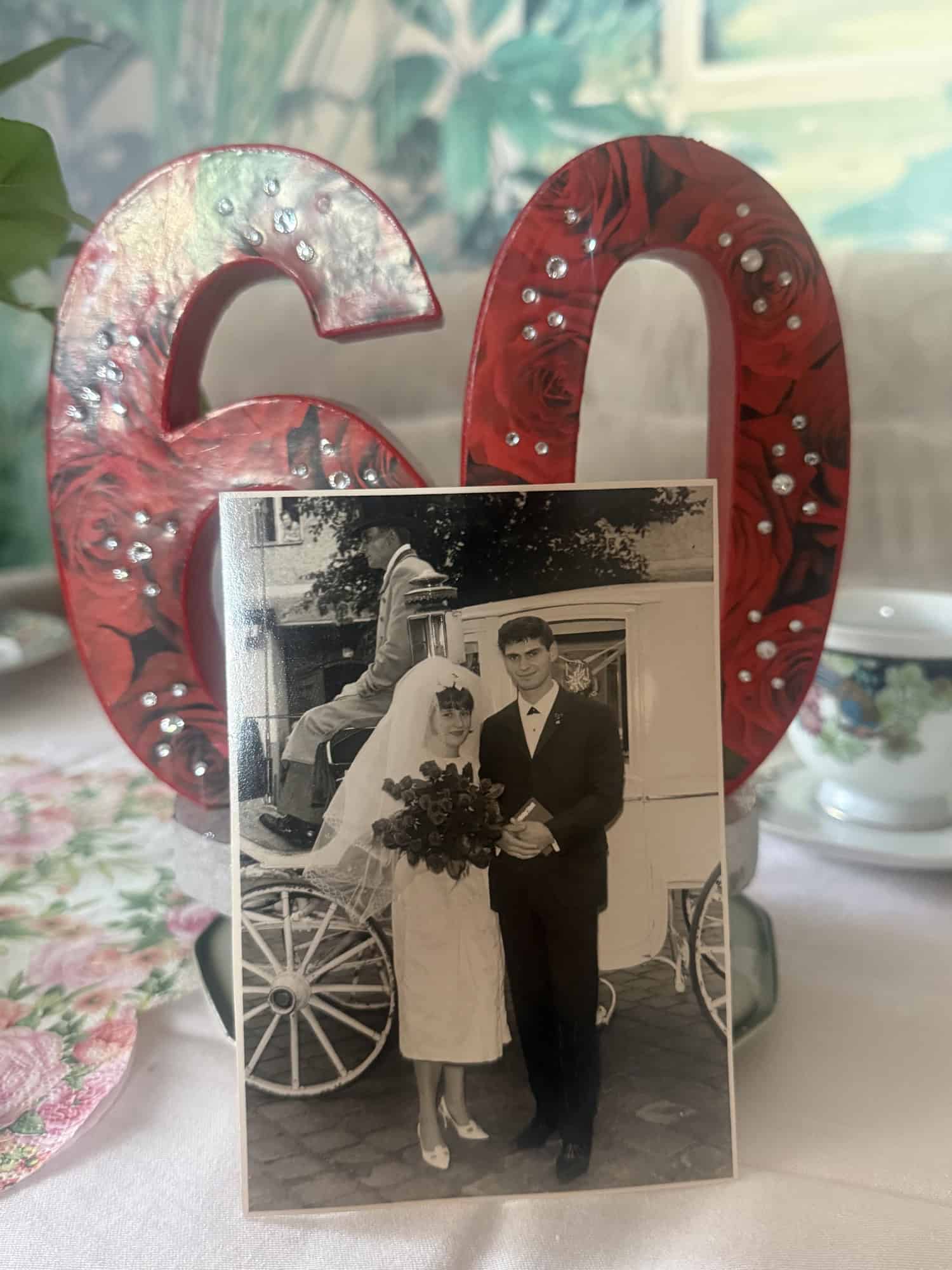 Ein altes schwarz-weißes Hochzeitsfoto des Paares steht neben einer roten Dekozahl 60.
