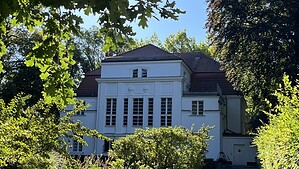 Die weiße Villa Worch, das heutige Kulturhaus Centre Bagatelle in Frohnau, zwischen Bäumen und Sträuchern.