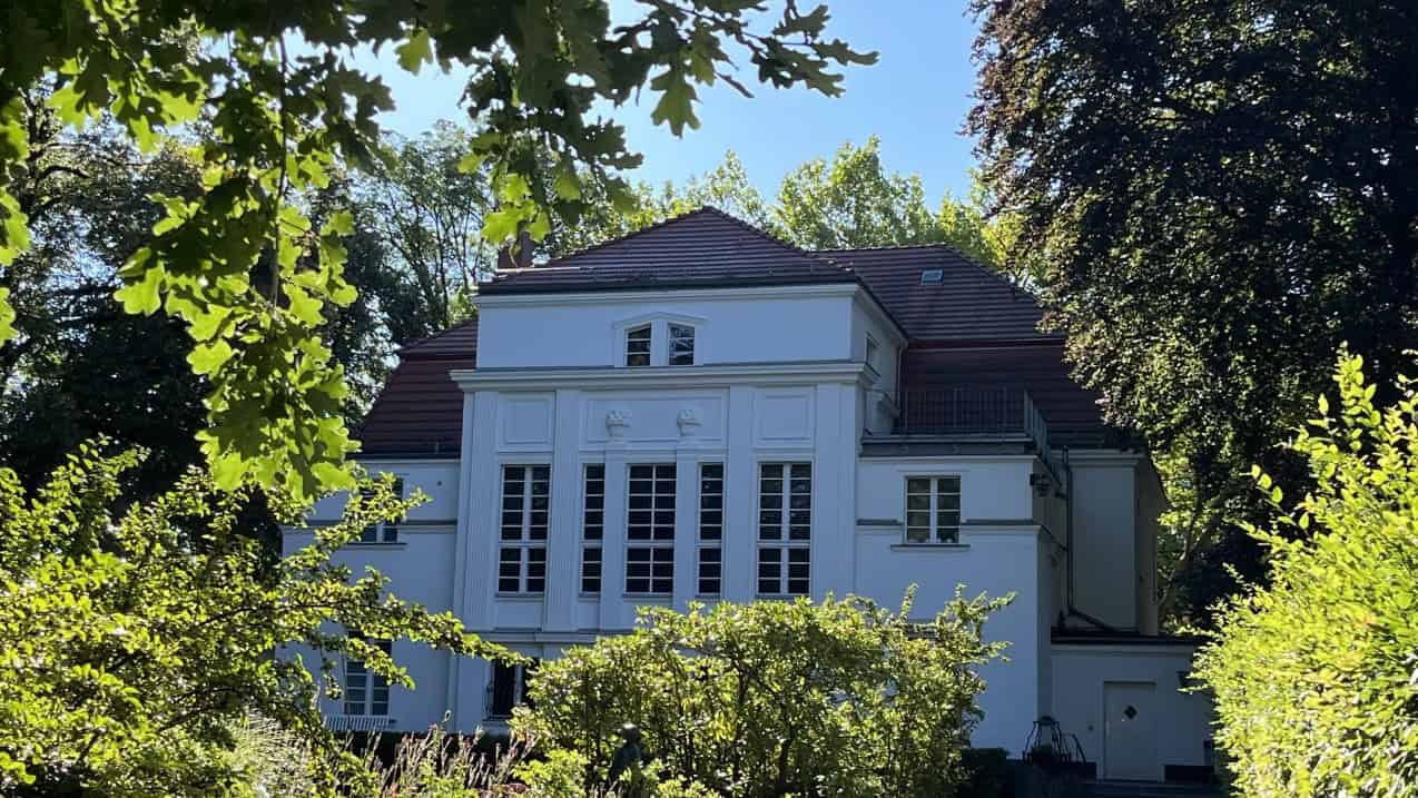 Die weiße Villa Worch, das heutige Kulturhaus Centre Bagatelle in Frohnau, zwischen Bäumen und Sträuchern.