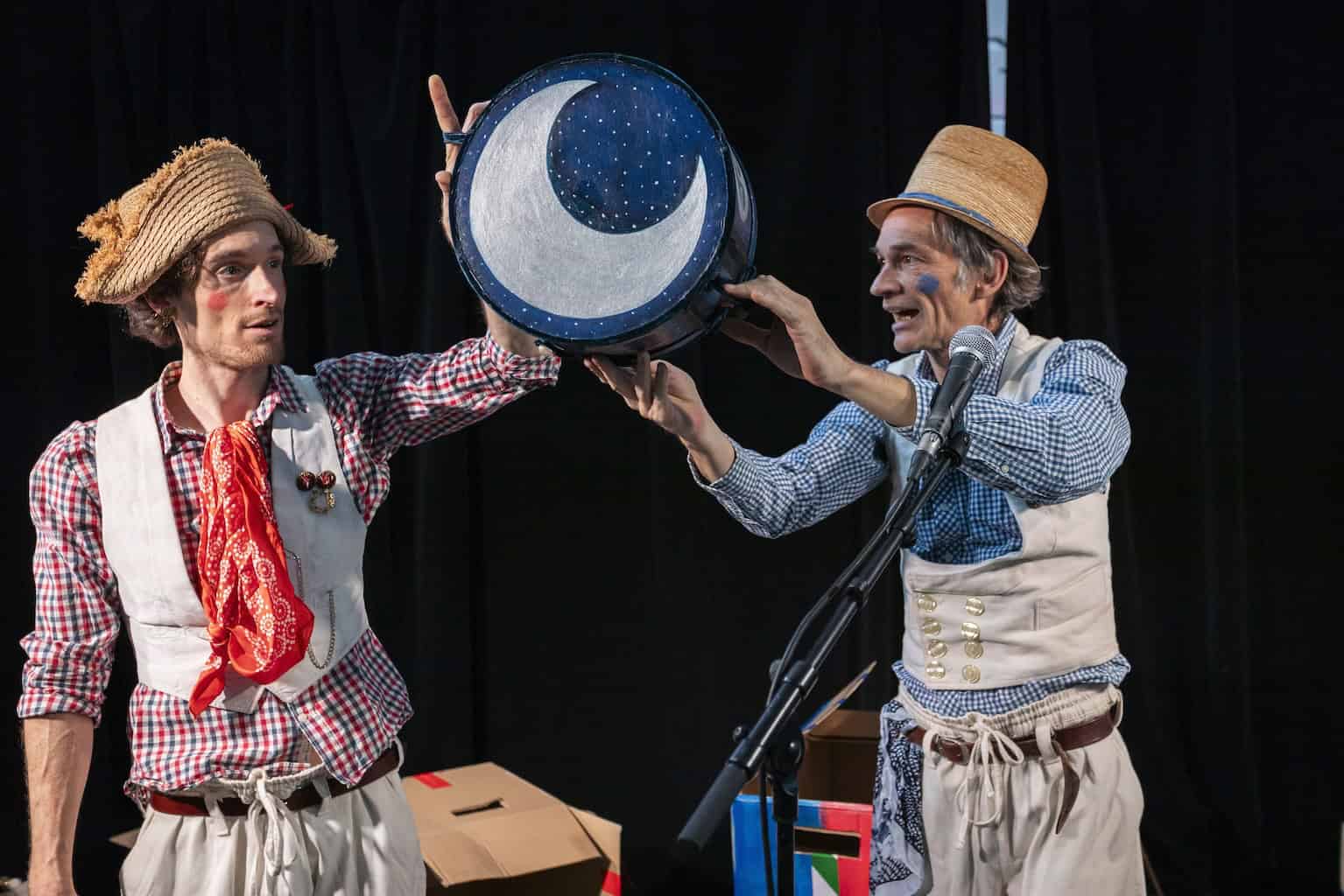 Zwei Darsteller des ATZE Musiktheaters mit Strohhüten und einer Mond-Requisite