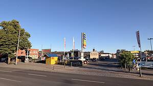 Blick von der Straße auf den EDEKA-Parkplatz am U-Bahnhof Wittenau mit Supermarkt, Werbetafeln und parkenden Autos.