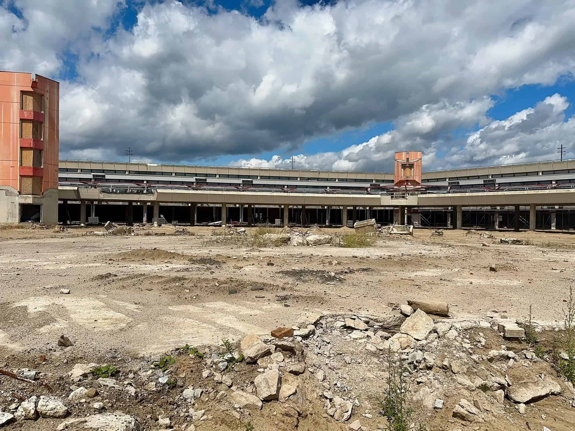 Das leerstehende, geschwungene Gebäude des ehemaligen Terminal A in Tegel hinter einer freigeräumten Sandfläche.