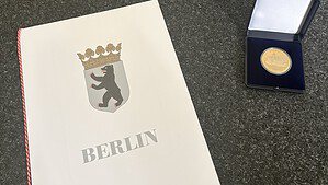Reinickendorfer Medaille im Etui, weiße Fuchs-Miniaturskulptur und Urkundenmappe mit dem Berliner Bärenwappen