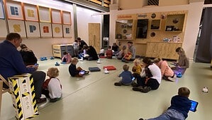 Kinder sitzen mit Tablets und kleinen Robotern auf dem Boden des Makerspace der Humboldt-Bibliothek.