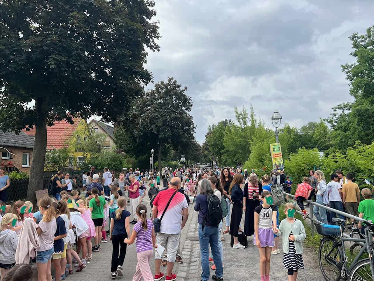 Kinder und Erwachsene stehen dicht gedrängt über die gesamte Breite einer gesperrten Wohnstraße.