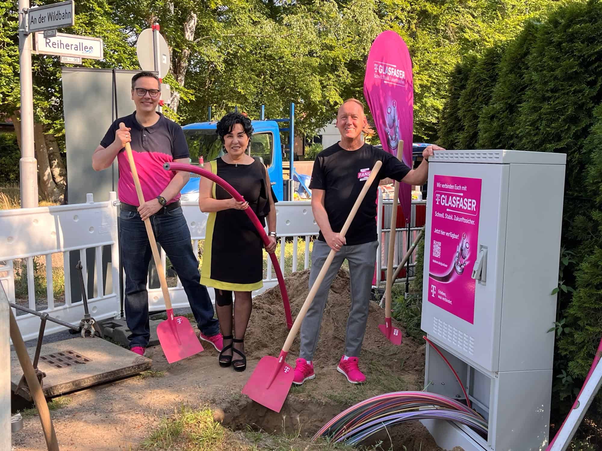 Symbolischer Spatenstich für den Glasfaserausbau in Heiligensee und Konradshöhe: Bezirksbürgermeisterin Emine Demirbüken-Wegner mit zwei Beteiligten und pinkfarbenen Spaten