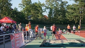 Kinder und Erwachsene auf einer Laufbahn neben einer Weitsprunggrube