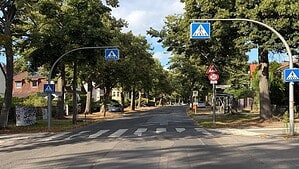 Zeltinger Straße an der Kreuzung Markgrafenstraße mit geflicktem Asphalt, Zebrastreifen und Bushaltestelle