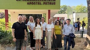 Zehn Personen stehen im Freien nebeneinander vor einem Gebäude mit der roten Aufschrift Ev. Gemeindezentrum Apostel Petrus.