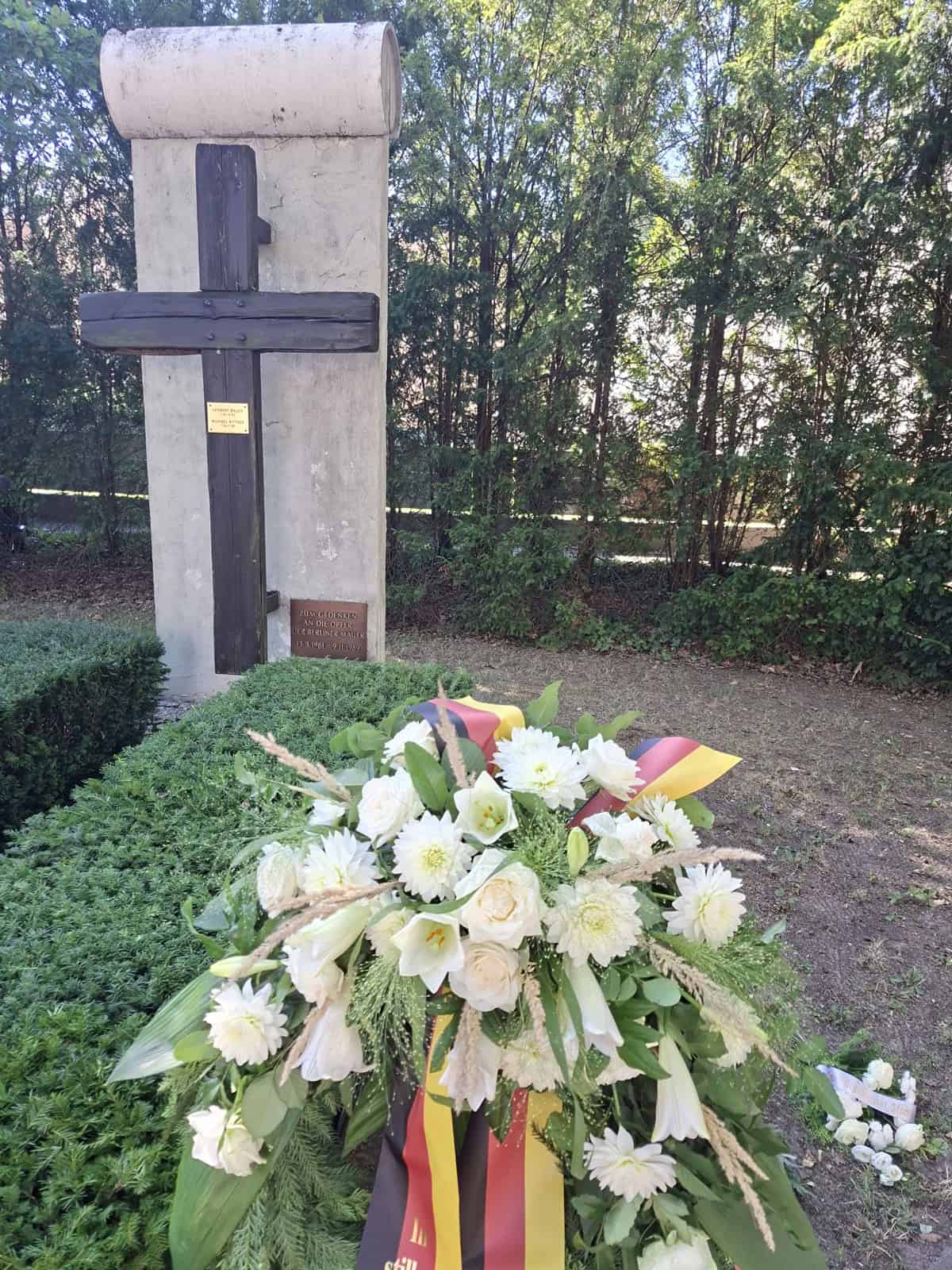 Gedenkkreuz vor einem Mauersegment am Edelhofdamm