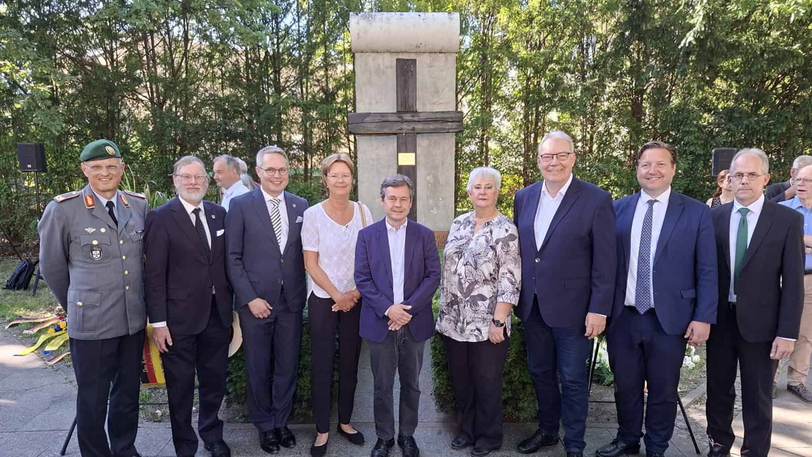 Gruppenfoto der Gäste vor dem Mauersegment nach der Gedenkveranstaltung