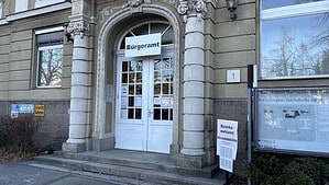 Eingang des Bürgeramts Reinickendorf-Ost in der Teichstraße 65 mit dem Schild Bürgeramt über der Tür und einem Aushang des Bezirkswahlamts daneben.