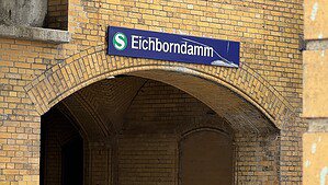 Blaues Stationsschild S-Bahnhof Eichborndamm über einem Ziegelbogen aus gelbem Klinker
