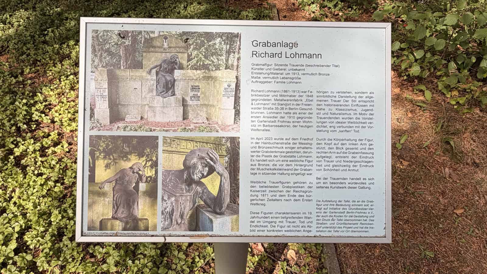 Info-Tafel auf einem Pfosten am Rand einer Grabanlage, links drei Fotos der Grabanlage und der Bronzefigur, rechts ein längerer Text zur Grabanlage Richard Lohmann.