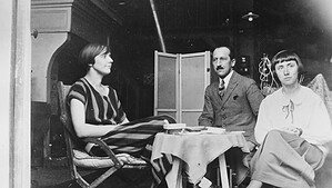 Historische Schwarzweißaufnahme: Drei Personen sitzen 1924 in einem Pariser Atelier um einen kleinen Tisch.