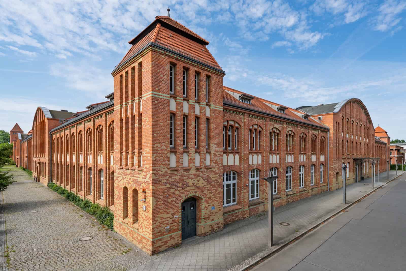 Eckansicht des Landesarchivs Berlin: ein mehrgeschossiger Backsteinbau mit Turm, daneben lange Gebäudeflügel entlang der Straße.