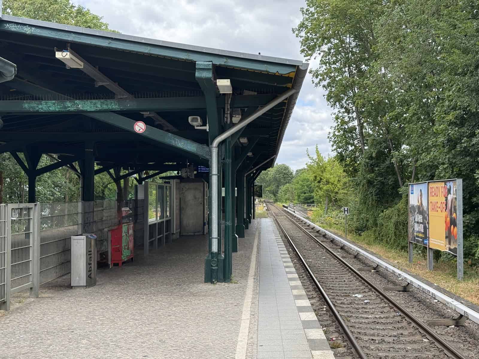 Überdachter Bahnsteig des S-Bahnhofs Eichborndamm mit Gleisen und Bäumen