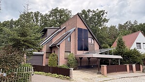 Einfamilienhaus mit Solarmodulen an der Giebelwand und einem Solar-Carport