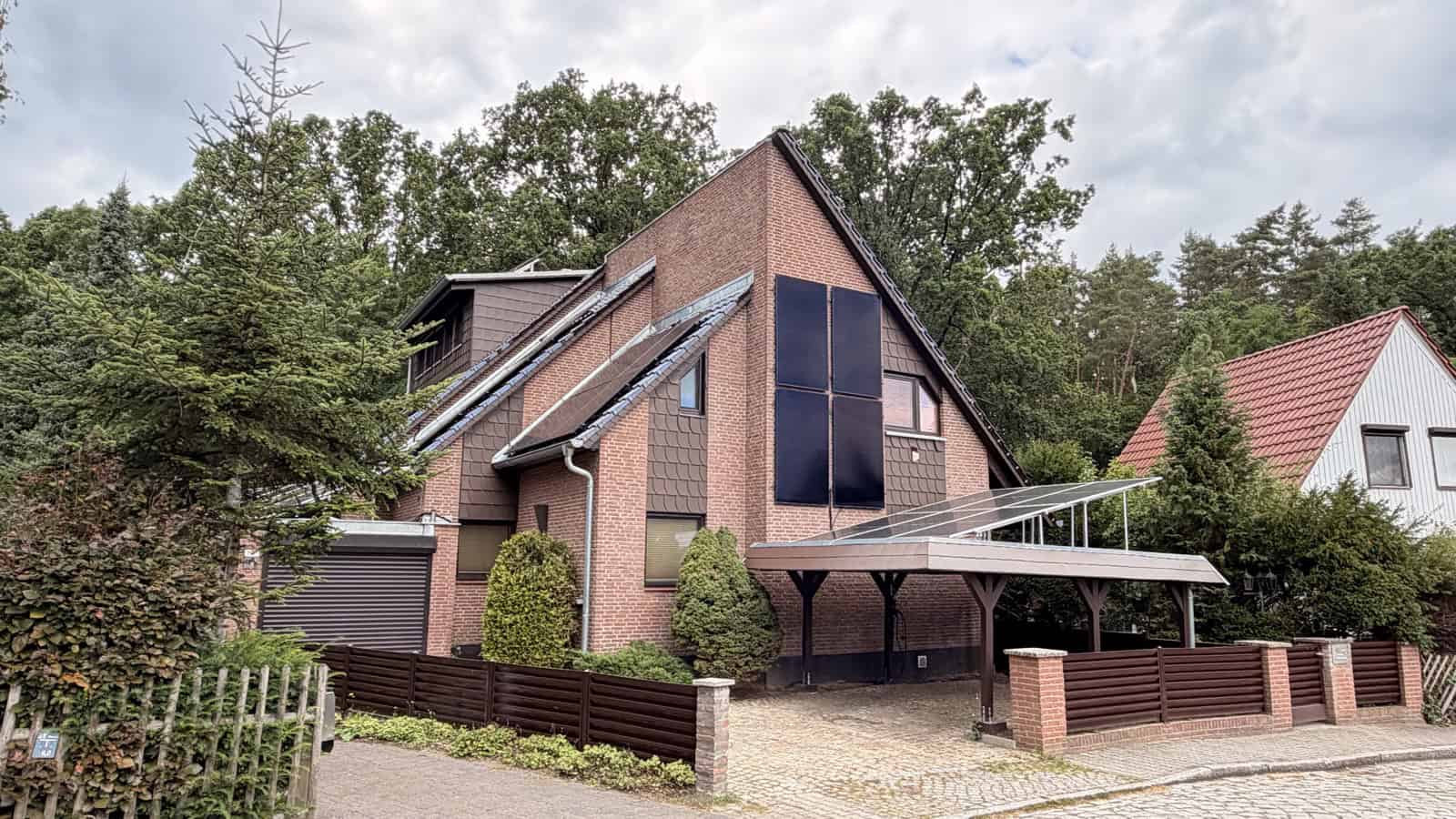 Einfamilienhaus mit Solarmodulen an der Giebelwand und einem Solar-Carport