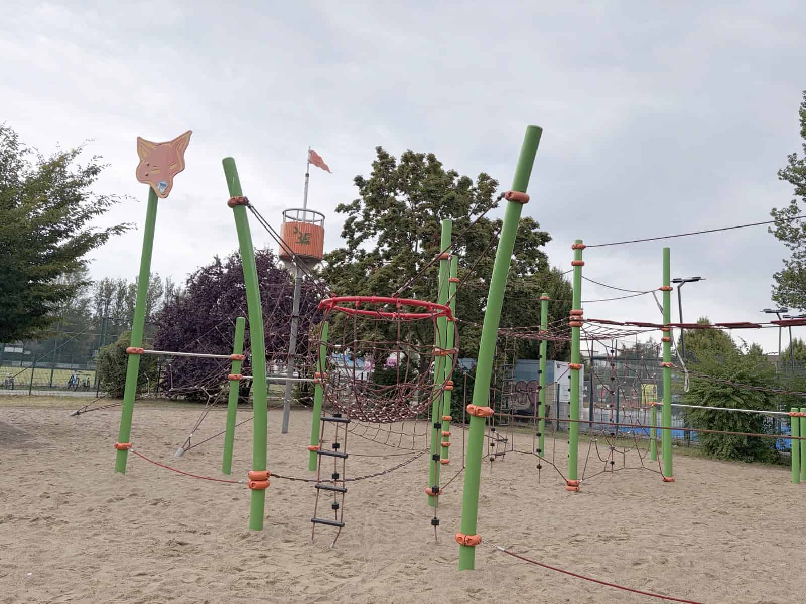 Spielplatz am Freiheitsweg mit grünen Kletterpfosten, Netzen und frischem Sand