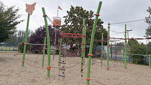 Spielplatz am Freiheitsweg mit grünen Kletterpfosten, Netzen und frischem Sand
