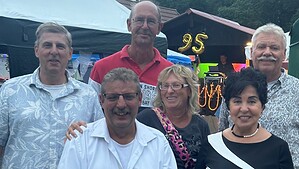 Sechs Personen stehen abends beim Jubiläumsfest dicht beieinander, im Hintergrund leuchtet eine Ballonzahl 95.