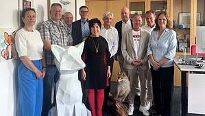 Elf Personen stehen für ein Gruppenbild in einem Büro des Bezirksamts Reinickendorf zusammen, vor ihnen eine weiße Fuchsskulptur.