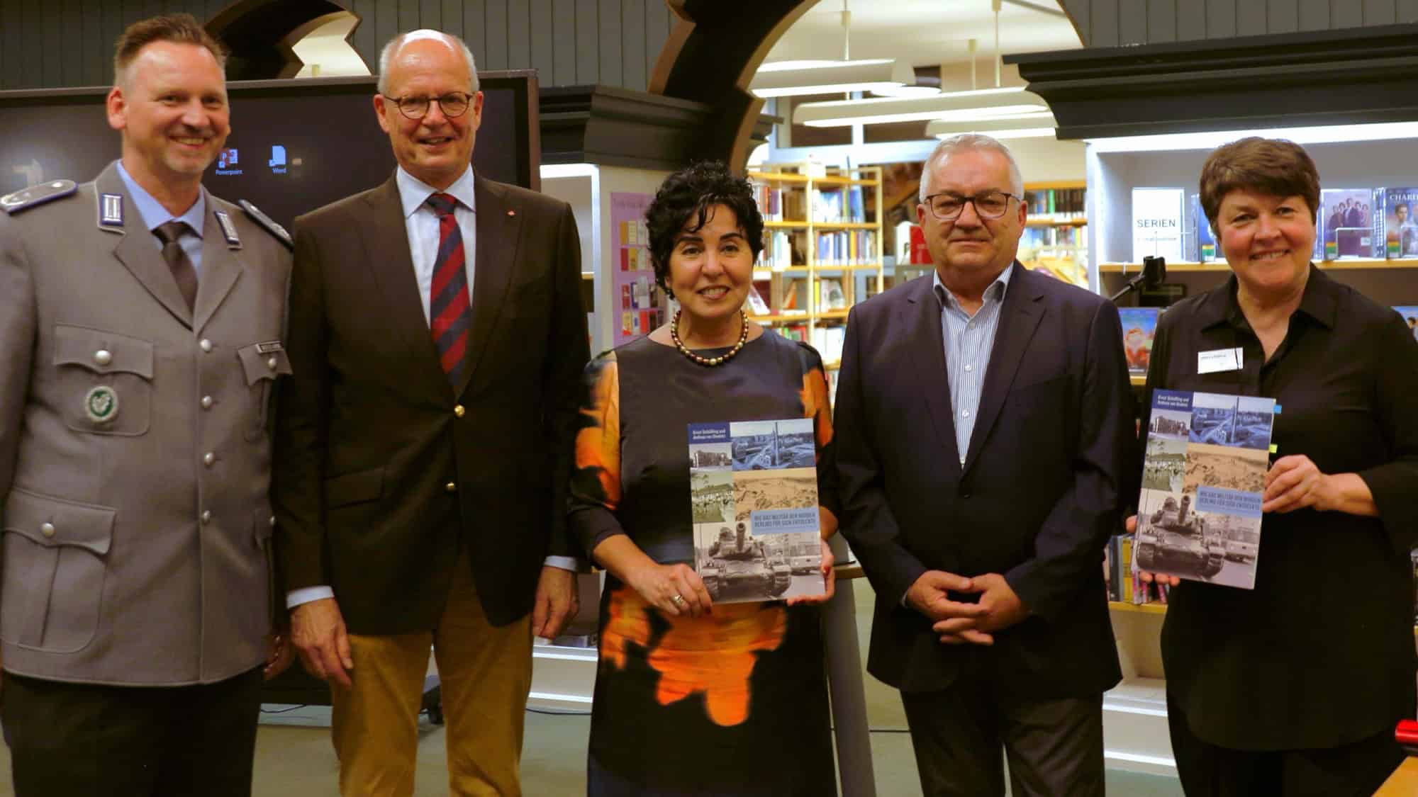 Fünf Personen stehen nebeneinander in der Humboldt-Bibliothek, zwei halten das Buch in den Händen
