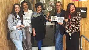 Fünf Frauen stehen vor dem Eingang des Kiezorts Brusi und halten Sticker der Einsamkeitskampagne hoch.