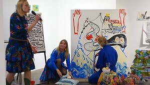 Drei Künstlerinnen der Gruppe JOKAklubi bei einer Performance vor einem großformatigen Gemälde