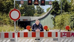 Mann lehnt an einer rot-weißen Absperrung vor der gesperrten Autobahnauffahrt zum Tegel-Tunnel