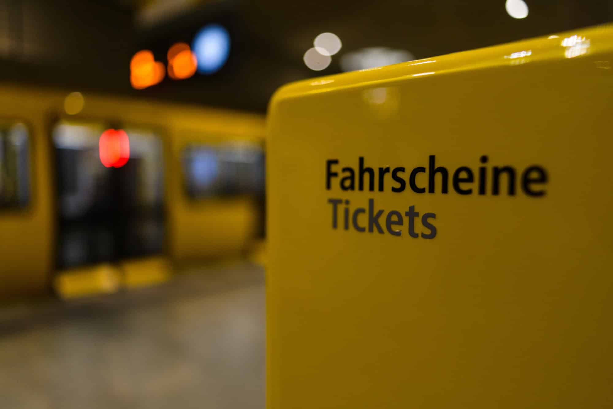 Gelber Fahrscheinautomat der BVG auf einem U-Bahnhof, im Hintergrund ein einfahrender Zug