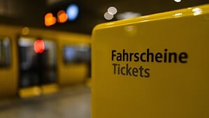 Gelber Fahrscheinautomat der BVG auf einem U-Bahnhof, im Hintergrund ein einfahrender Zug