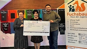 Drei Personen halten im Fuchsbau einen großen Scheck über 300 Euro, daneben steht ein Aufsteller des Hauses der Jugend.
