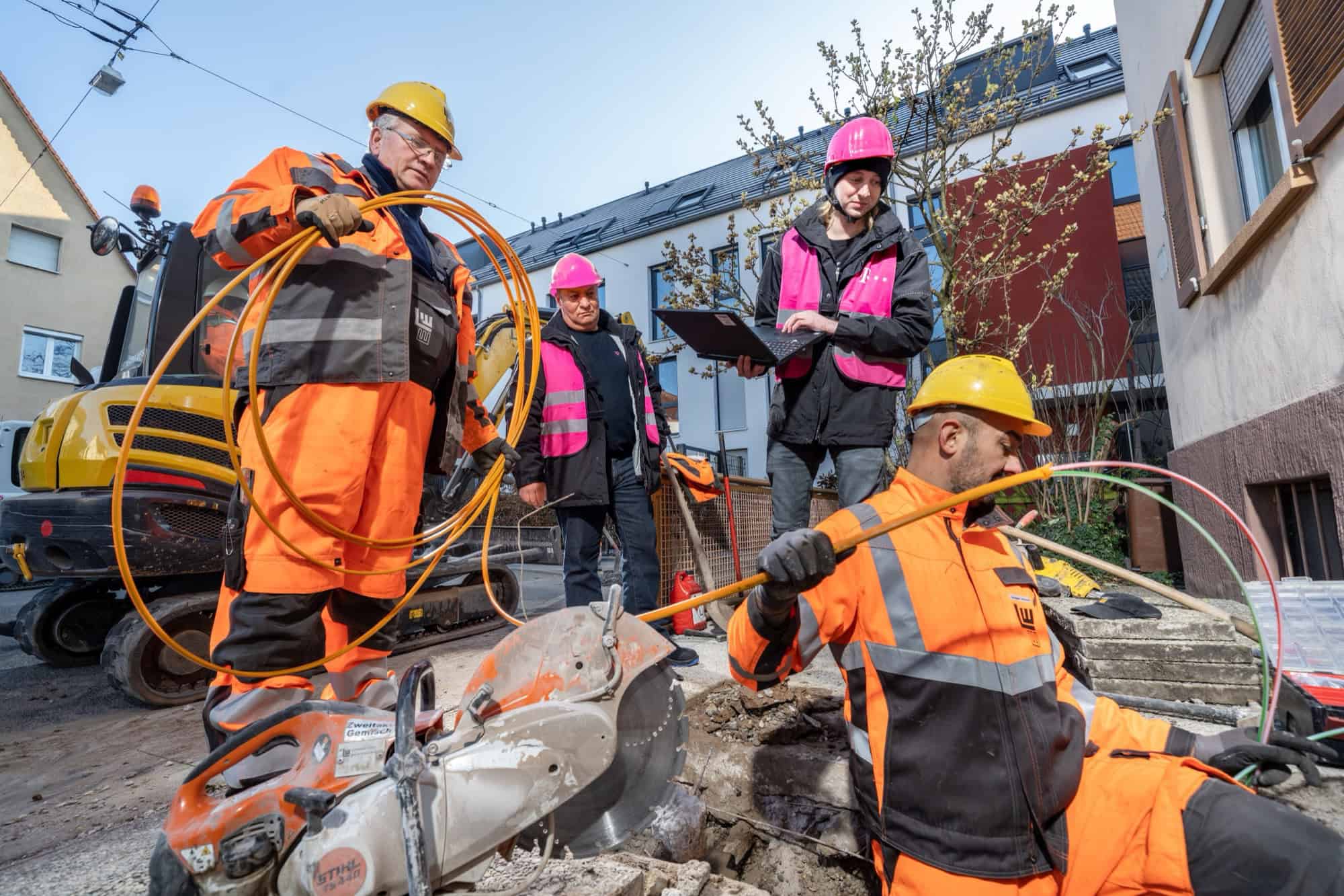 Bauarbeiter verlegen Erdkabel in einem Wohngebiet.