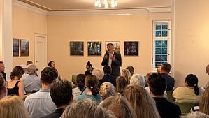 Ein Mann spricht mit Mikrofon vor einem voll besetzten Saal im Centre Bagatelle