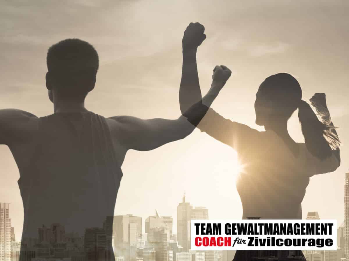 Grafik in Sepiatönen: Ein Mann und eine Frau stehen mit dem Rücken zum Betrachter vor einer Stadtsilhouette im Gegenlicht und recken die Fäuste in die Höhe, unten rechts der Schriftzug „Team Gewaltmanagement, Coach für Zivilcourage“.