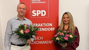 Björn Hawlitschka und Sevda Boyraci mit Blumensträußen vor einem Banner der SPD-Fraktion Reinickendorf