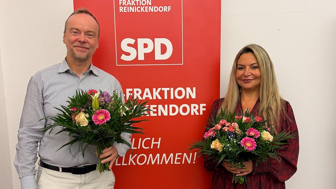 Björn Hawlitschka und Sevda Boyraci mit Blumensträußen vor einem Banner der SPD-Fraktion Reinickendorf