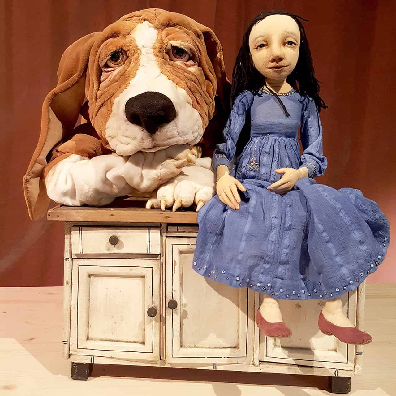 Zwei Puppen aus dem Theaterstück Einmal Schneewittchen bitte sitzen auf einer kleinen weißen Kommode.