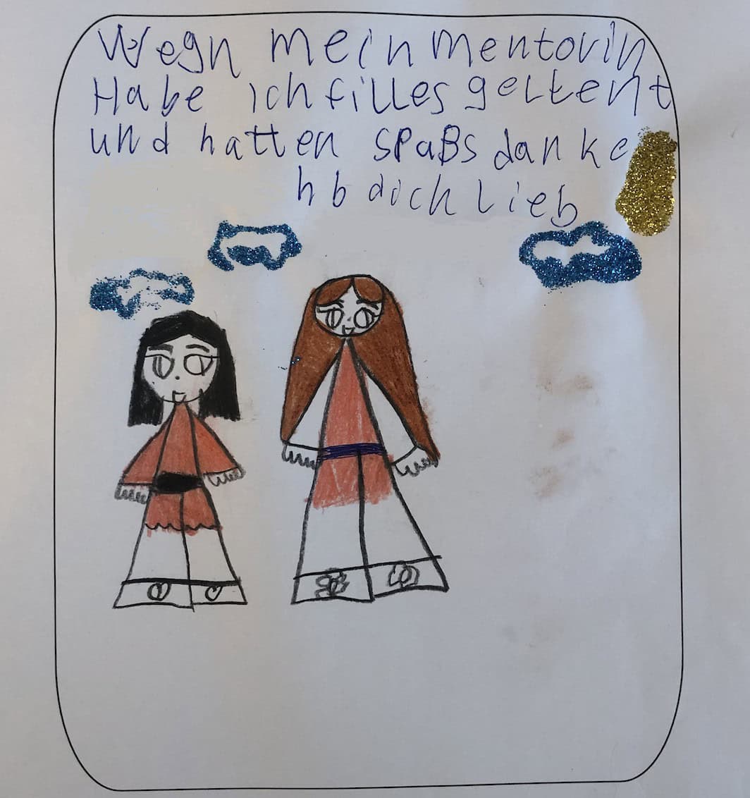 Kinderzeichnung mit zwei Figuren, einem Mädchen mit schwarzen Haaren und einer größeren Frau mit braunen Haaren, darüber Glitzerwolken und ein handgeschriebener Dank an die Mentorin.