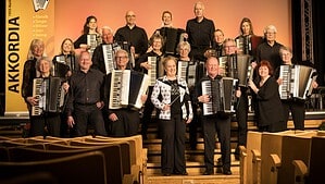 Gruppenbild des Akkordeonorchesters Akkordia 1935 Berlin mit rund 25 Musikerinnen und Musikern und ihren Instrumenten auf einer Bühne
