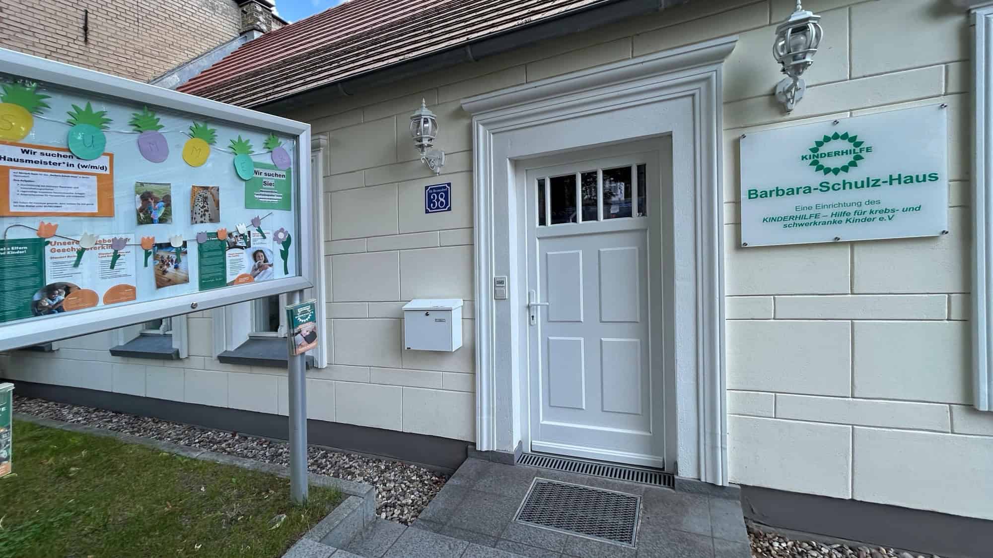Eingang des Barbara-Schulz-Hauses in Alt-Hermsdorf mit Schaukasten und Schild des Vereins Kinderhilfe