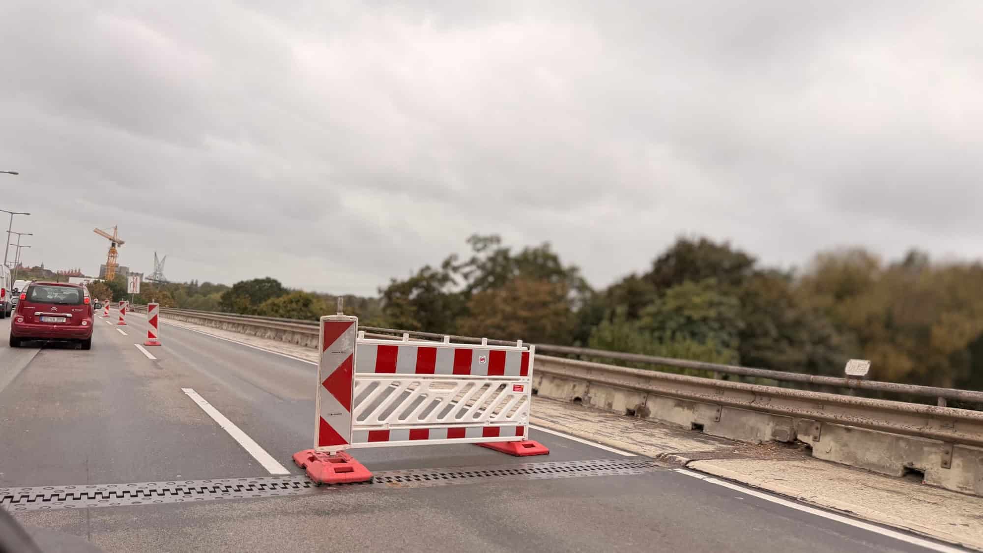 Rot-weiße Absperrung auf dem rechten Fahrstreifen einer Autobahnbrücke, links fließt der Verkehr weiter.