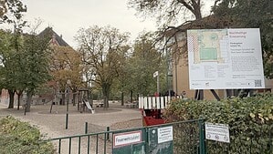 Blick auf einen Schulhof mit Spielgeräten. Rechts und im Hintergrund stehen Schulgebäude.