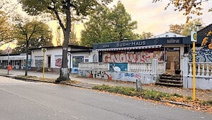 Eine einstöckige Ladenzeile in Berlin Reinickendorf mit dem leerstehenden Sushi Haus, das mit Graffiti beschmiert ist und vor dem herbstliches Laub liegt.